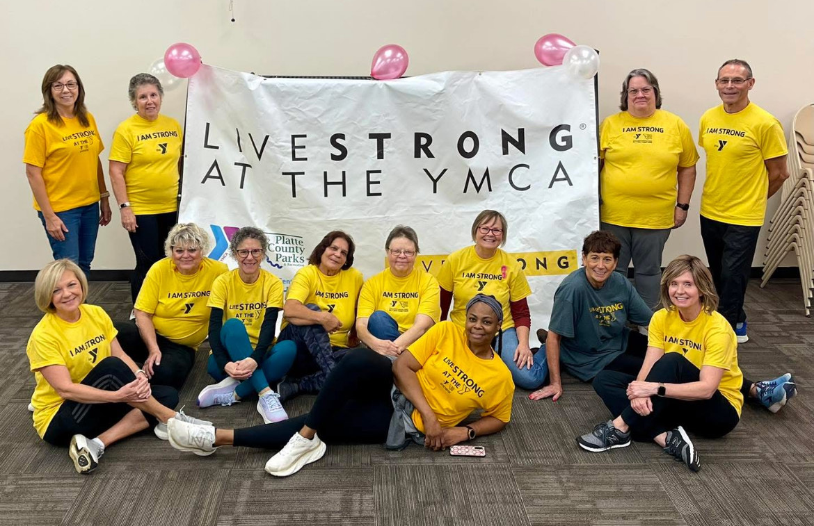 Group photo of LIVESTRONG participants and cancer survivors posing in their yellow LIVESTRONG shirts with a YMCA LIVESTRONG banner.
