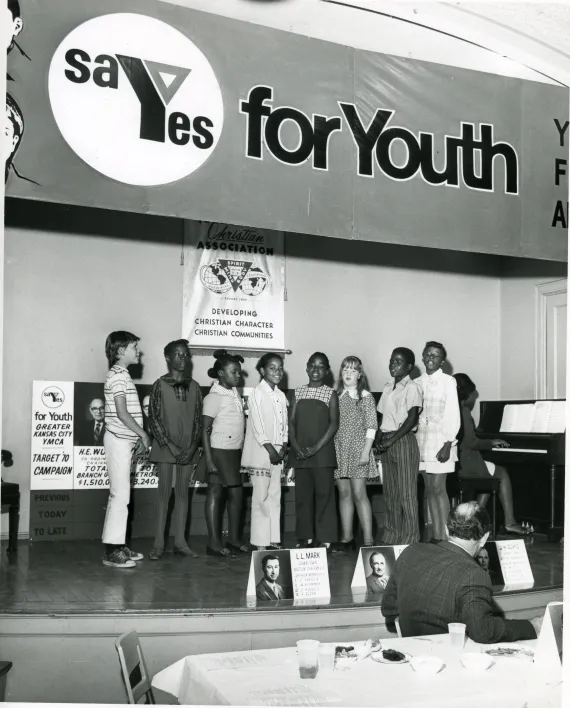 Image of children on stage talk at an assembly for "Say Yes to Youth".